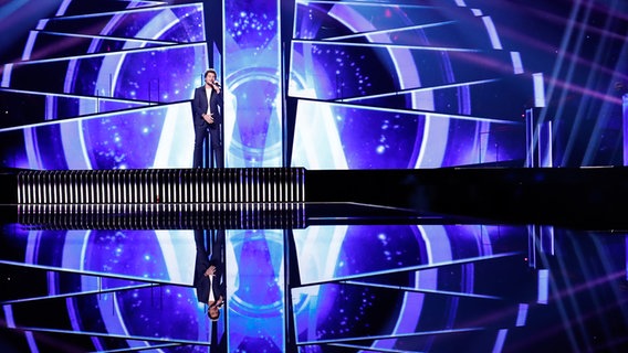 Amir im dunkelblauen Anzug auf der Bühne. © eurovision.tv Foto: Andres Putting (EBU)
