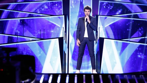 Amir steht im dunkelblauen Anzug auf der Bühne. © eurovision.tv Foto: Andres Putting (EBU)