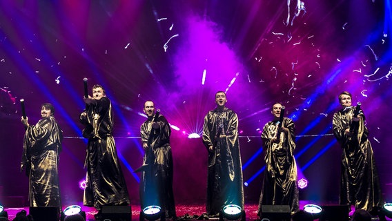 Sechs Sänger von Gregorian in Mönchskutte mit Konfettikanone auf der Bühne © Edel Records 
