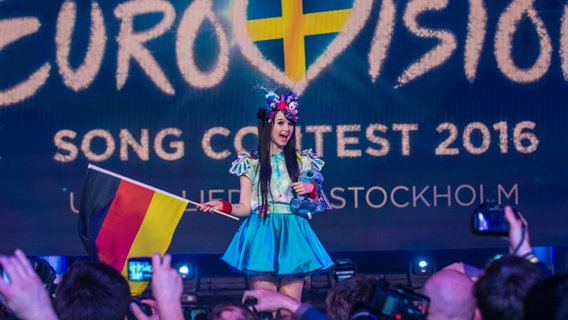 Jamie-Lee Kriewitz mit einer Deutschlandfahne vor dem ESC-Logo. © NDR Foto: Rolf Klatt