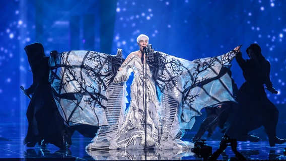 Nina Kraljić trägt eine weiß-silberne Robe mit großen Ärmeln, die wie Äste in einem Baum bedruckt sind. © NDR/Rolf Klatt Foto: Rolf Klatt