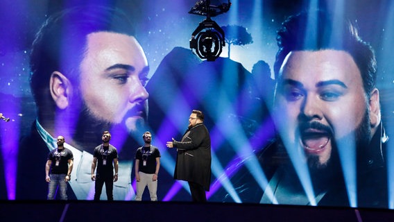 Jacques Houdek steht auf der Bühne, im Hintergrund sind seine Porträts auf die Bühnenwand projeziert. © Eurovision.tv Foto: Thomas Hanses