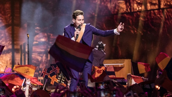 Der Niederländer Douwe Bob singt nach vorne gebeugt ganz dicht an den Fans, die Fahnen hochhalten © NDR Foto: Rolf Klatt