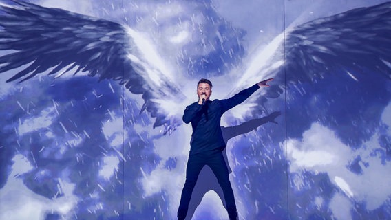 Sergey steht vor der LED-Wand auf die große Flügel projiziert sind. © eurovision.tv Foto: Andres Putting (EBU)