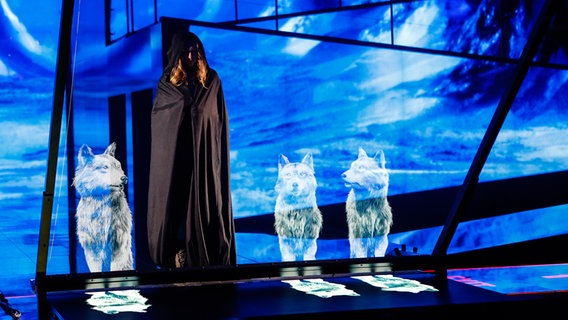 Ivan betritt die Bühne in einem dunklen Umhang, projizierte Wölfe begleiten ihn. © eurovision.tv Foto:  Thomas Hanses (EBU)