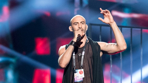 Der Sänger Francois Micheletto hebt den Arm. © eurovision.tv Foto: Andres Putting (EBU)