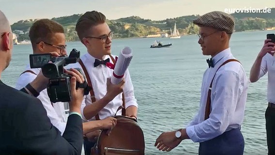 Mikolas Josef holt eine Papierrolle aus seinem Rucksack.  