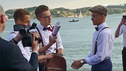 Mikolas Josef holt eine Papierrolle aus seinem Rucksack.  