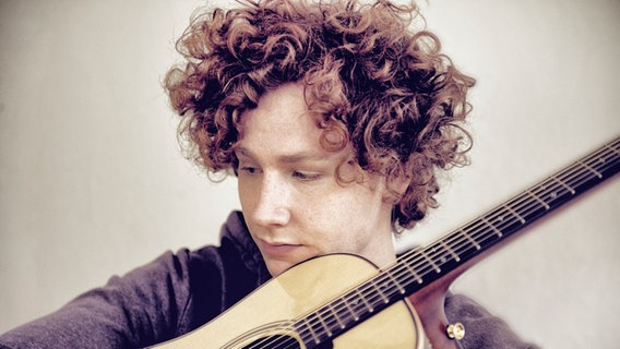 Der Sänger und Songwriter Michael Schulte hält eine Gitarre im Arm.  Foto: Sven Sindt