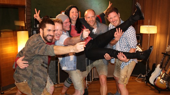 Die fünf Mitglieder der Band VoXXclub heben Choreografin Nici Grandison hoch und lachen in die Kamera. Die fünf Mitglieder der Band VoXXclub heben Choreografin Nici Grandison hoch und lachen in die Kamera. © Marcel Stober Foto: Marcel Stober