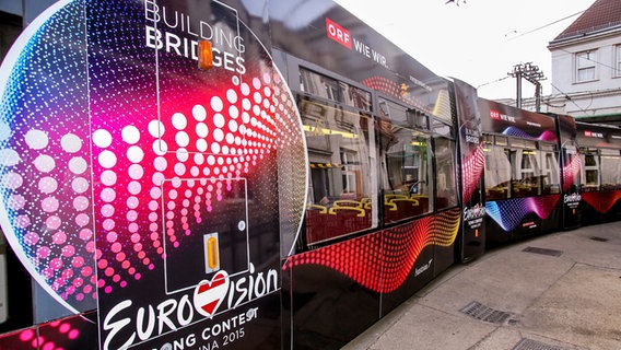 Eine Straßenbahn in Wien ist mit dem Logo des 60. ESC und dem Slogan "Building Bridges" bedruckt © ORF/Günther Pichlkostner 